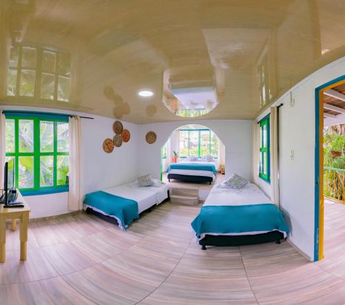 a room with two beds and a table and windows at Eco Hotel las Palmas in Armenia