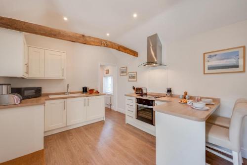 a kitchen with white cabinets and a wooden floor at Marlborough House Forge in Saxtead