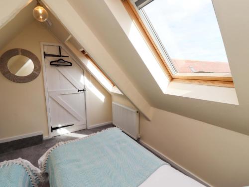 a attic bedroom with a skylight and a window at Barleycorn Cottage in Belford