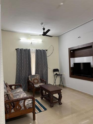 a living room with furniture and a flat screen tv at Sihi 2BHK in Mysore