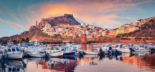 a bunch of boats docked in a harbor with a city at La Pulvarera in Castelsardo