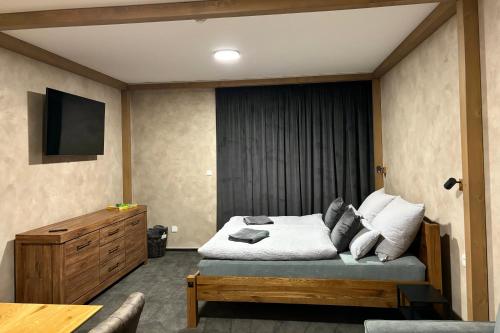 a bedroom with a bed with a tv on the wall at Luxusní Apartmán Domovjanka - KNĚHYNĚ in Bílá