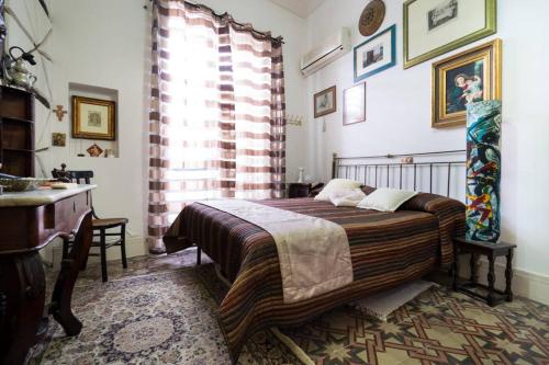 Schlafzimmer mit einem Bett, einem Schreibtisch und einem Fenster in der Unterkunft Regina Reginella in Syrakus