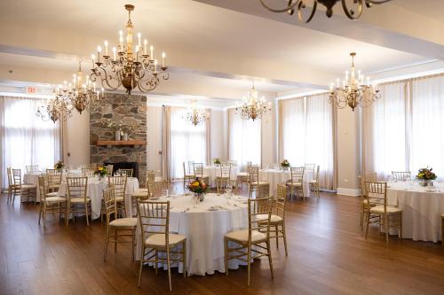 a room with white tables and chairs and chandeliers at The Mimslyn Inn in Luray