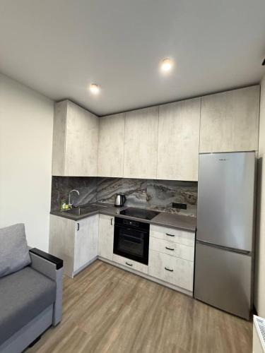 a kitchen with white cabinets and a refrigerator and a couch at Апартаменти ВІП вул Під Голоском 15 б 9-2 in Lviv