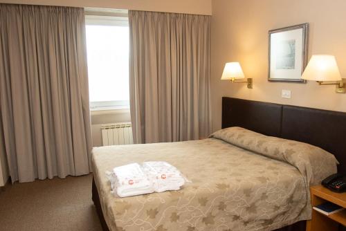 a hotel room with a bed with two towels on it at Comodoro Hotel in Comodoro Rivadavia