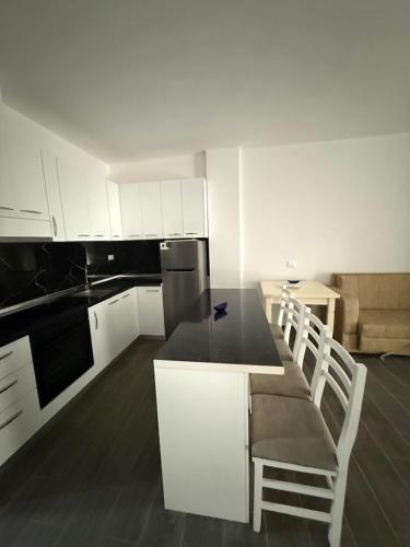 a kitchen with white cabinets and a table and chairs at Caca Apartments in Golem