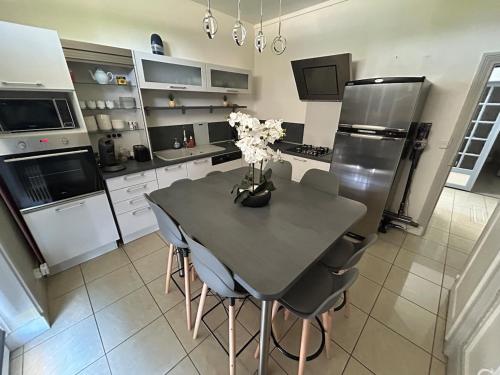 a kitchen with a table with chairs and a refrigerator at La maison des Ducs, terrasse, BBQ, Proche centre in Nevers