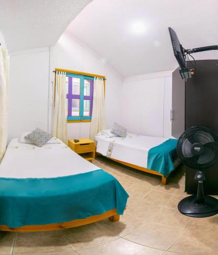 a room with two beds and a fan in it at Eco Hotel las Palmas in Armenia