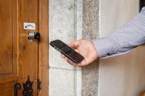 a person holding a cell phone in their hand next to a door at Klosterherberge Solothurn Self Check-in in Solothurn