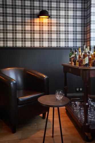 a bar with a leather chair and a table at The Originals Boutique, Hôtel La Colonne de Bronze, Saint-Valéry-sur-Somme in Saint-Valery-sur-Somme