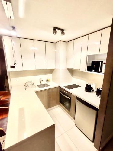 a white kitchen with a sink and a microwave at Exclusive and Secure Apartment Parque Arauco Las Condes in Santiago