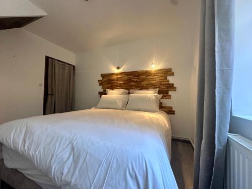 a bedroom with a white bed with a brick wall at La Floraison in Molesmes