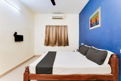 a bedroom with a bed with a blue wall at Hotel O Nr galaxy residency in Chennai