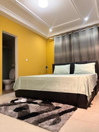 a bedroom with a large bed and a yellow wall at Duende in Pointe-Noire