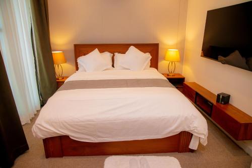 a bedroom with a large bed with white sheets at Maison Luxe Apartments in Nkunjila