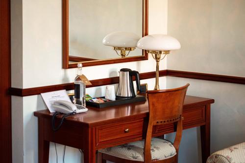 a room with a desk with a telephone and a lamp at Phi Hotel Dei Medaglioni in Correggio