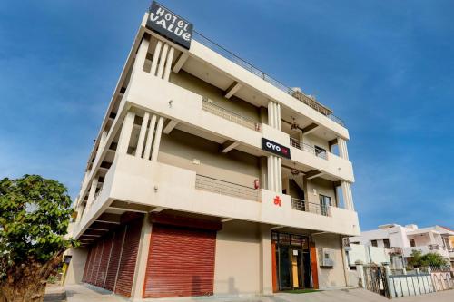 a tall white building with a sign on it at Hotel O Value in Jabalpur