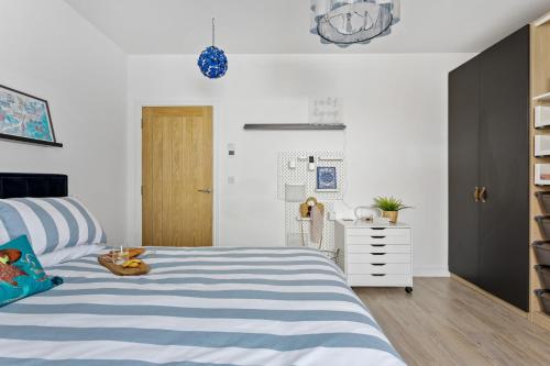 a bedroom with a blue and white bed and a dresser at Sea Holly House - Where Architecture Meets the Ocean in Beer