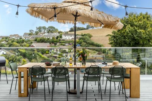 a table and chairs under an umbrella on a deck at Sea Holly House - Where Architecture Meets the Ocean in Beer