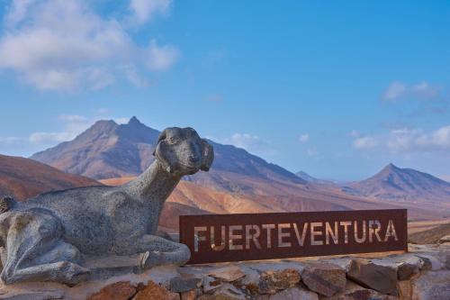 a statue of a dog sitting next to a sign at MarVillaFuerte - Appart Air-Conditioned Swimming Pool & Private Jacuzzi in Villaverde