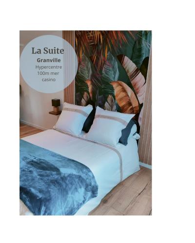 a bedroom with a large bed with a painting on the wall at La Suite Granville in Granville