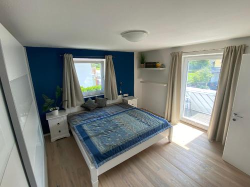 1 dormitorio con 1 cama con paredes azules y 2 ventanas en Alpine Schmiede Chalet, en Ehrwald