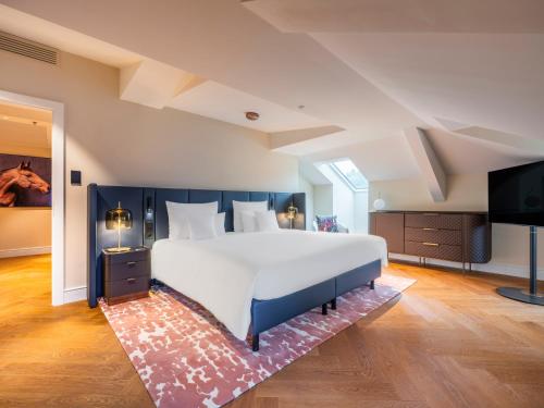 a large bedroom with a large bed and a flat screen tv at Steigenberger Icon Europäischer Hof Baden Baden in Baden-Baden
