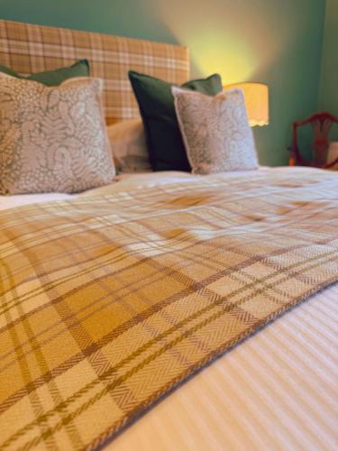 a bed with a plaid blanket on top of it at The Old Hunting Lodge at The Talbot Inn in Tenbury
