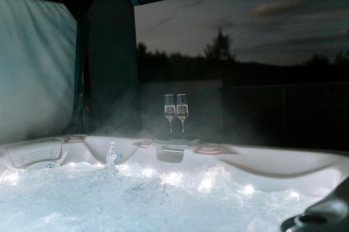 a bath tub with two wine glasses in it at Aura Wellness Apartment in Vrbno pod Pradědem