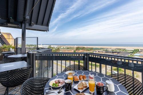 a table with food on a balcony with a view of the ocean at Novotel Deauville Plage in Deauville