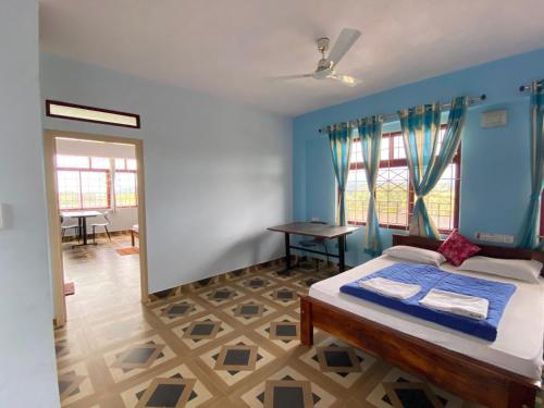 a bedroom with a bed with blue walls and windows at Janaki Stay in Somvārpet