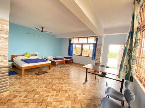 a room with a bed and a table and chairs at Janaki Stay in Somvārpet