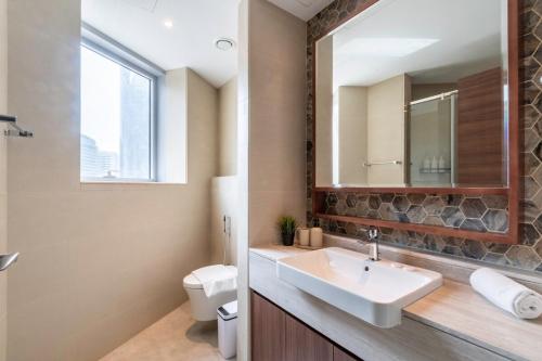a bathroom with a sink and a toilet and a mirror at GYL Holiday Homes -Imperial Avenue - Luxury Retreat Apt with Burj Khalifa Pool View - Near Dubai Mall in Dubai