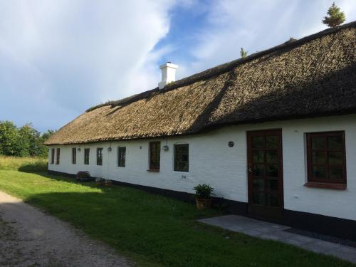 una antigua casa blanca con techo de paja en Øster Mogensbæk #4 en Sindal