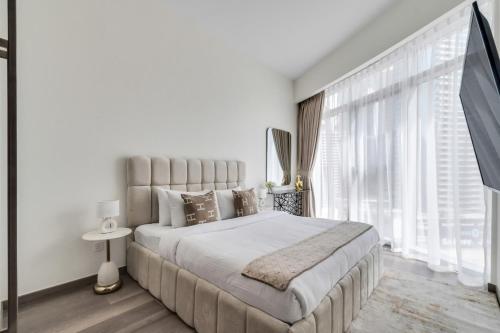 a white bedroom with a large bed and large windows at GYL Holiday Homes -Imperial Avenue - Luxury Retreat Apt with Burj Khalifa Pool View - Near Dubai Mall in Dubai