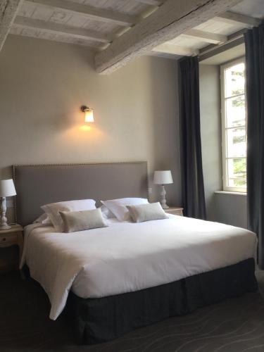 a bedroom with a large bed with white sheets and pillows at Boutique Hôtel La Villa MONTESQUIEU in Laudun