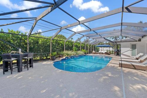 a swimming pool with a pergola on a patio at Bimini Breeze - Updated Island Retreat with Pool & Beach Access in West Palm Beach