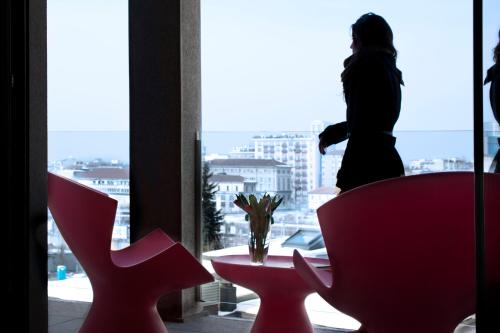 a woman is looking out of a window at a table and chairs at Zambala Luxury Apartments in Milan