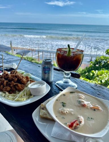 a table with plates of food and a drink on the beach at Hotel Casa Miramar in Tamanique