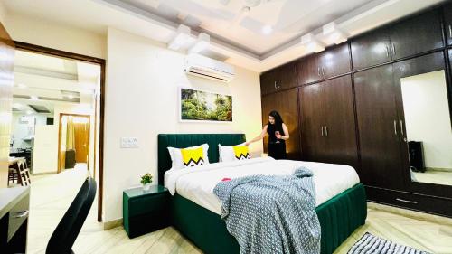 a woman standing next to a bed in a room at Olive Service Apartments Rohini in New Delhi
