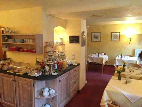 a kitchen with a counter and a dining room with tables at Villa Benz Hotel garni in Schwetzingen