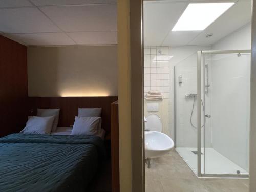 a bedroom with a bed and a sink and a shower at Hotel De Venne in Genk