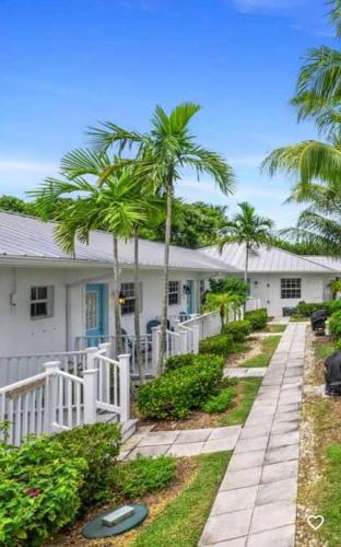 a white house with palm trees and a walkway at Seahorse Beach Bungalows in Fort Pierce