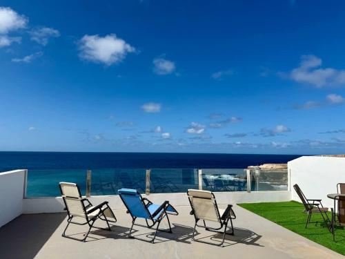 a patio with chairs and a table and the ocean at House on the beach WIFI Ajuy Fuerteventura in Ajuy