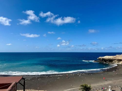a beach with people on the sand and the ocean at House on the beach WIFI Ajuy Fuerteventura in Ajuy