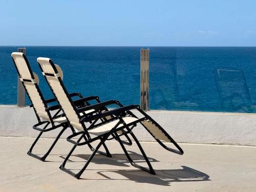 a pair of chairs sitting on a ledge overlooking the ocean at House on the beach WIFI Ajuy Fuerteventura in Ajuy