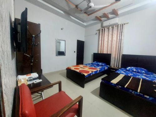 a bedroom with two beds and a table and a chair at HostHub Guest House Gulshan iqbal in Karachi
