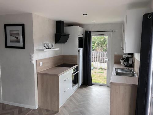 una cucina con armadi bianchi e una porta che conduce a un cortile di Le Refuge sablais a Les Sables-dʼOlonne