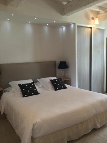 a bedroom with a large white bed with black pillows at Boutique Hôtel La Villa MONTESQUIEU in Laudun